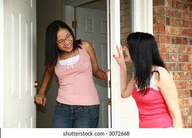 Young Woman Answering Door For Friend.