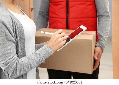 Young woman appending signature after receiving parcel from courier at home, closeup - Shutterstock ID 541020331
