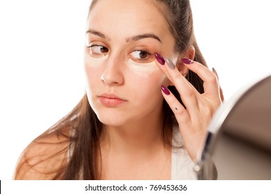 A young woman applies a concealer under the eyes