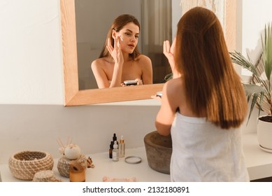 A Young Woman Applies Moisturizer To Her Face In Her Sun Bath. Daily Routine, Hydration And Skin Care Concept