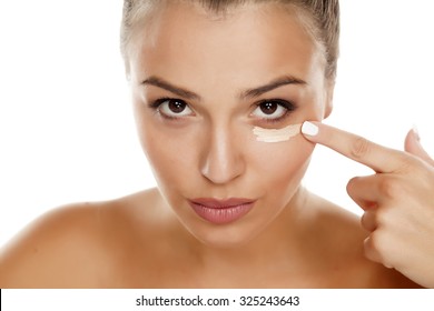 young woman apply concealer under the eye