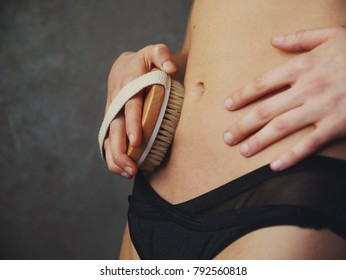 young woman apply dry brush on her abdomen