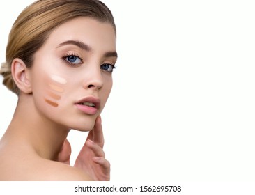 Young woman applying 4 color samples of facial foundation cream or corrector at her face. Beauty model with perfect fresh skin and long eyelashes. Makeup Concept.