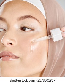 A Young Woman Applying Antiaging Facial Serum To Her Face And Skin. Beautiful Muslim Girl Wearing A Hijab Trying Retinol With A Dropper As Her Skincare Routine And Beauty Treatment Regime