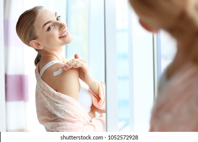 Young Woman Applying Body Cream At Home