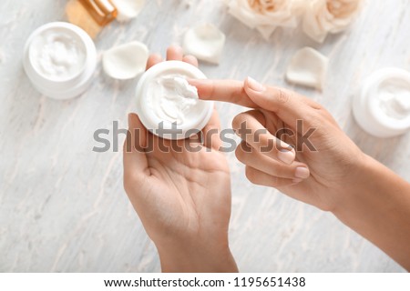 Young woman applying body cream, closeup