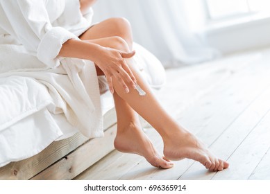 Young Woman Applying Body Lotion On Legs