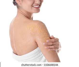 Young woman applying body scrub on her shoulder against white background