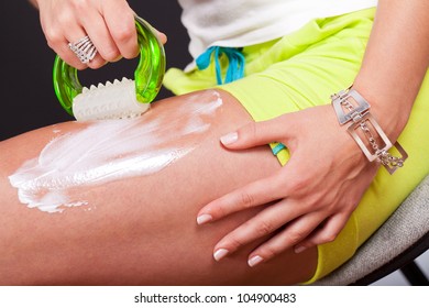 Young Woman Applying Cellulite Cream On Her Leg