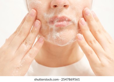 Young woman applying cleansing foam to her face close-up on white background. - Powered by Shutterstock