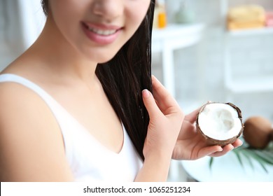 Young Woman Applying Coconut Oil Onto Hair At Home