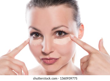 Young Woman Applying Concealer On White Background