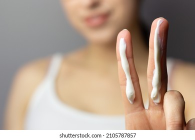 Young woman applying the correct amount of sunscreen for face and neck. - Shutterstock ID 2105787857