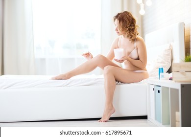 Young Woman Applying Cream On Legs