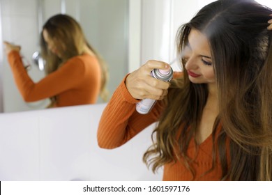 Young woman applying dry shampoo on her hair. Fast and easy way to keep hair clean with dry shampoo. Focus on the hand with spray. - Shutterstock ID 1601597176