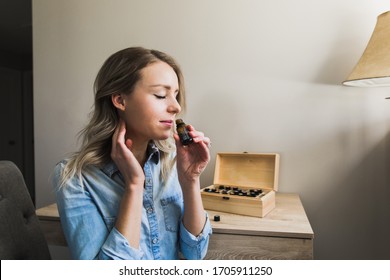 Young Woman Applying Essential Oils To Her Neck And Smelling Open Bottle