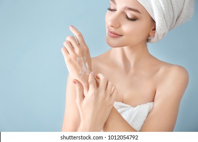 Young Woman Applying Hand Cream On Color Background