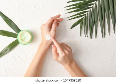 Young Woman Applying Hand Cream At Light Table