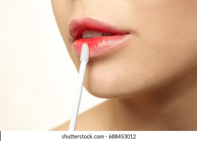 Young Woman Applying Lip Gloss, Closeup