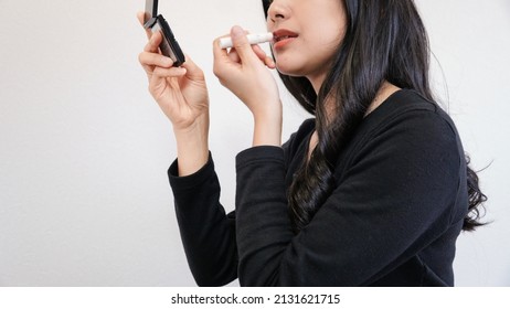 Young Woman Applying Lipstick, Upper Body Shot 