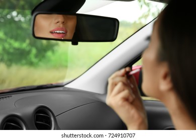 Young woman applying makeup in car - Powered by Shutterstock