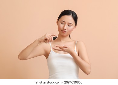 Young Woman Applying Makeup Foundation On Color Background