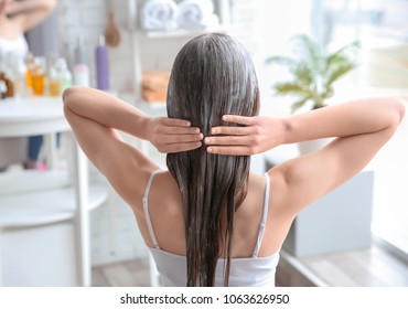 Young Woman Applying Mask Onto Hair At Home