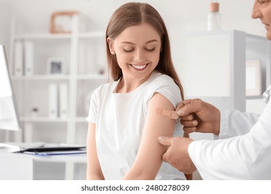 Young woman applying medical patch after vaccination in clinic