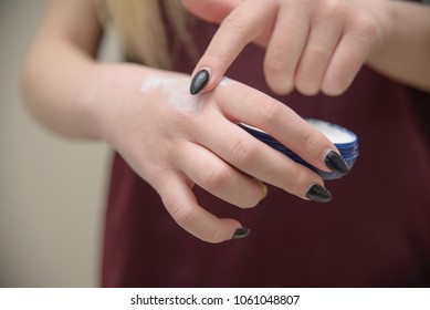 young woman applying moisturizer on her hand with very dry skin and deep cracks with cream closeup - Shutterstock ID 1061048807