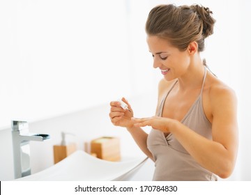 Young Woman Applying Nail Polish In Bathroom