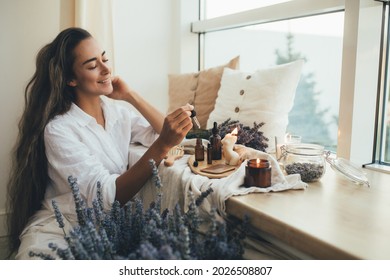 Young woman applying natural organic essential oil on hair and skin. Home spa and beauty rituals. Skin care. - Shutterstock ID 2026508807