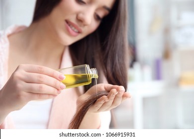 Young Woman Applying Oil Onto Hair At Home