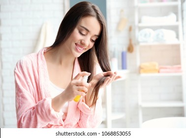 Young Woman Applying Oil Onto Hair In Bathroom