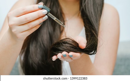 Young Woman Applying Oil Onto Her Hair