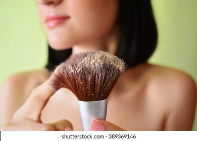 Young woman applying powder with brush