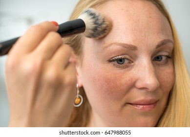 Young woman applying powder make-up
