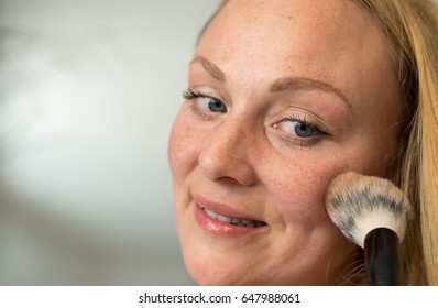 Young woman applying powder make-up