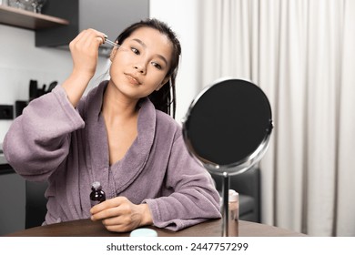 Young Woman Applying Serum In Front Of Mirror, Skin Care Routine, Healthy Lifestyle, Beauty Blogger Concept - Powered by Shutterstock