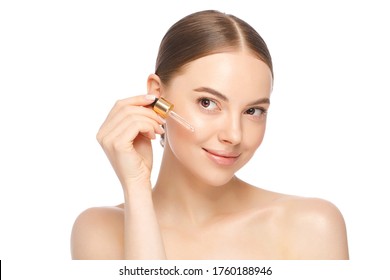 Young Woman Applying Serum To Her Face, Looking Away, Isolated On White Background. Beautiful Model Girl With Perfect Clean Fresh Skin.Treatment Or Cosmetic Ads Concept