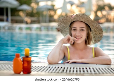 Young woman applying sunscreen lotion sitting on poolside. Sunscreen solar cream uv protection concept.