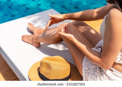 Young woman applying sunscreen lotion at swimming pool to take care of her skin, Summer vacation concept