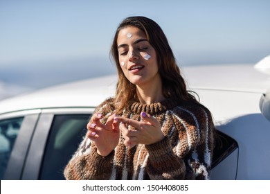 Young Woman Applying Sunscreen On Her Face In Snowy Mountains In Winter, In Sierra Nevada, Granada, Spain. Female Wearing Winter Clothes.