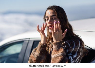 Young Woman Applying Sunscreen On Her Face In Snow Landscape