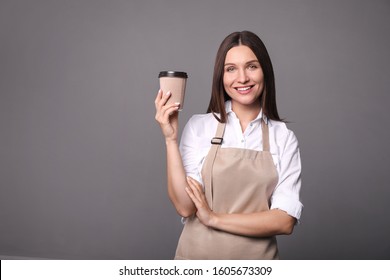 
Young Woman In Apron With Coffee On  Gray Background. Barista Concept