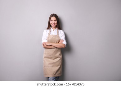 
Young Woman In An Apron On A Gray Background.