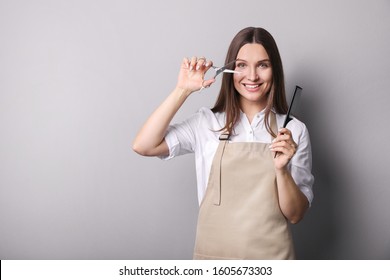 Young woman in apron on grey background. Hairdresser concept - Powered by Shutterstock