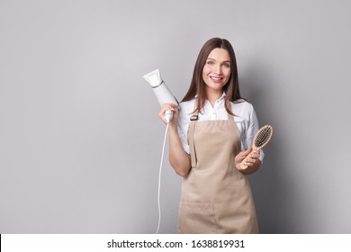 Young woman in apron on grey background. Hairdresser concept - Powered by Shutterstock