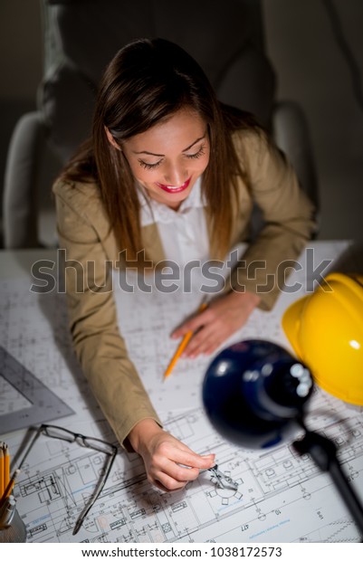 Young woman architect constructor analyzing
blueprint at desk in office. Top
view.