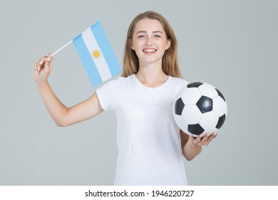 Young woman with Argentina flag and soccer ball in her hands, looking straight into the camera, isolated on gray background. Argentine women's football. - Powered by Shutterstock