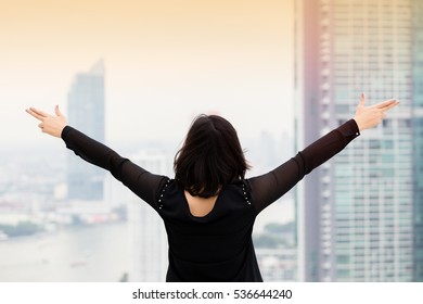 Young woman with arms raised on towers in bangkok city thailand.